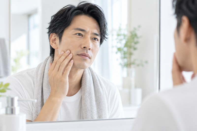 鏡の前で肌の調子を確認する男性のイメージ 必要なら、このあと