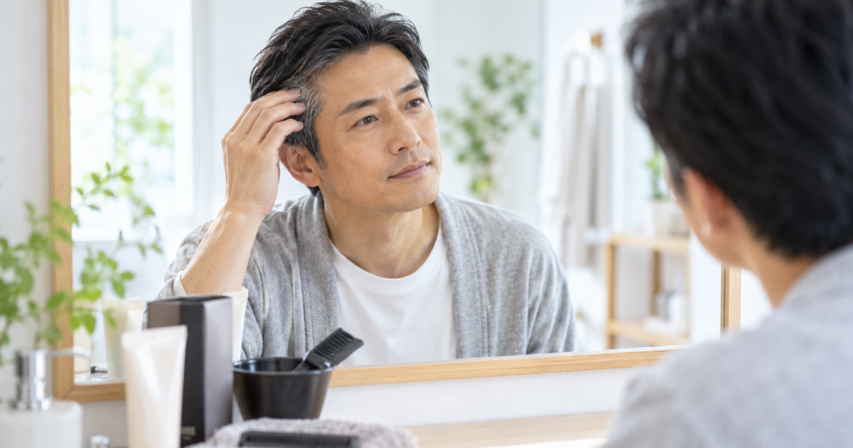 鏡の前でこめかみの白髪を確認する男性