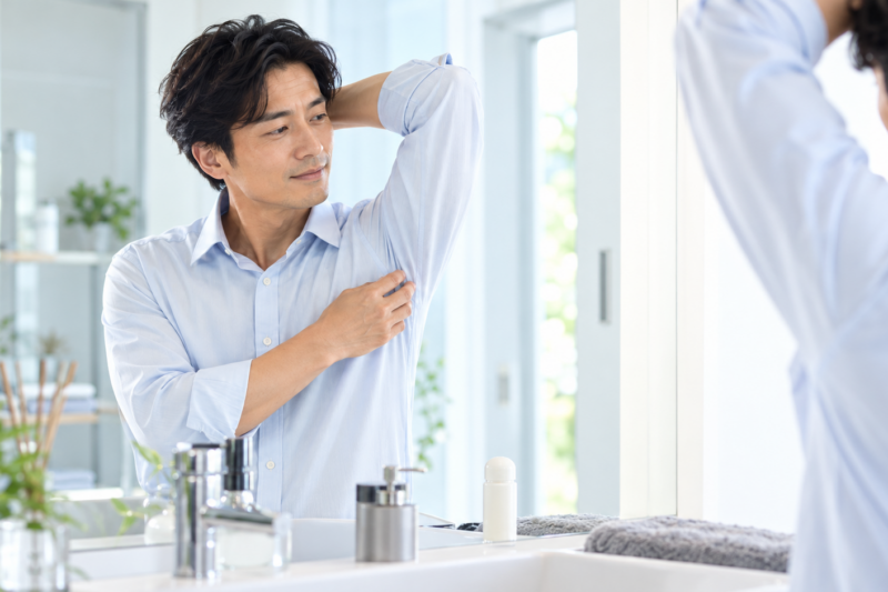 鏡の前でわきの身だしなみを確認する40代男性